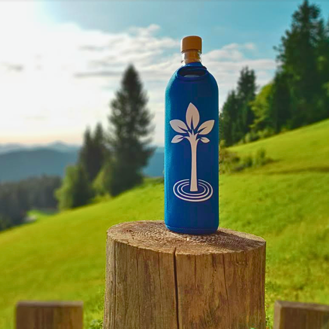 Man running an outdoor race, smiling, with a green glass water bottle in a neoprene sleeve featuring a white lotus design placed on the right side of the image.